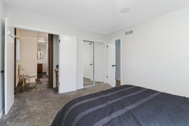 bedroom with connected bathroom and dark colored carpet