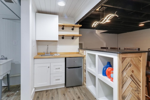 kitchen featuring sink, stainless steel fridge, butcher block counters, white cabinets, and light wood-type flooring