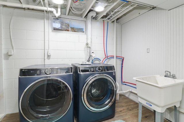 laundry area with hardwood / wood-style flooring, separate washer and dryer, and sink