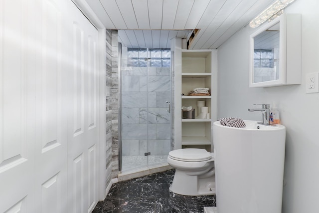 bathroom featuring a shower with shower door and toilet