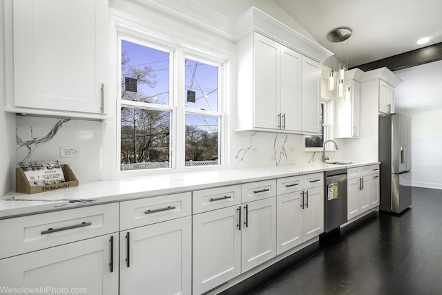 kitchen with sink, appliances with stainless steel finishes, white cabinetry, hanging light fixtures, and backsplash