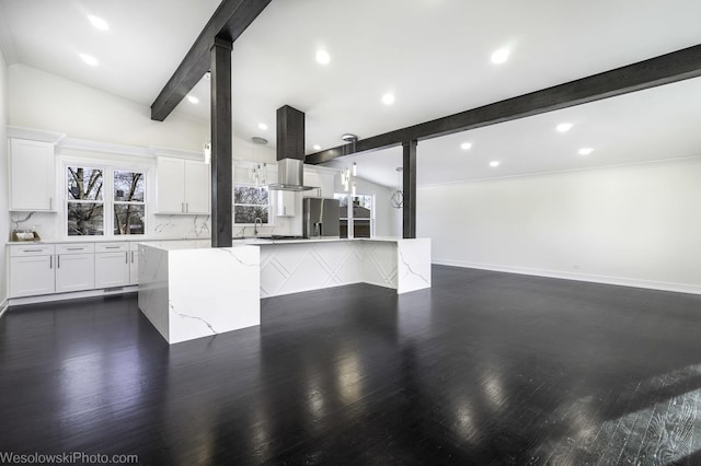 kitchen with lofted ceiling with beams, white cabinetry, backsplash, stainless steel refrigerator with ice dispenser, and light stone countertops