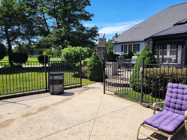 view of gate featuring a lawn and a patio