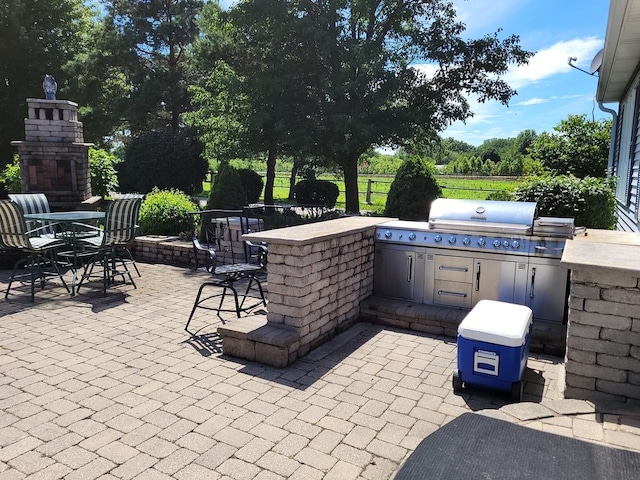 view of patio with grilling area, exterior bar, exterior kitchen, and an outdoor stone fireplace