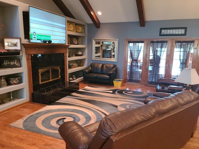 living room with built in shelves, french doors, lofted ceiling with beams, light wood-type flooring, and a fireplace