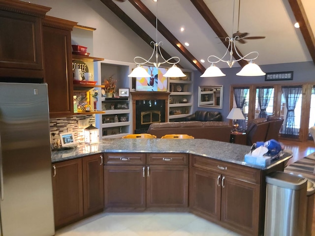 kitchen featuring hanging light fixtures, tasteful backsplash, stone countertops, and stainless steel fridge