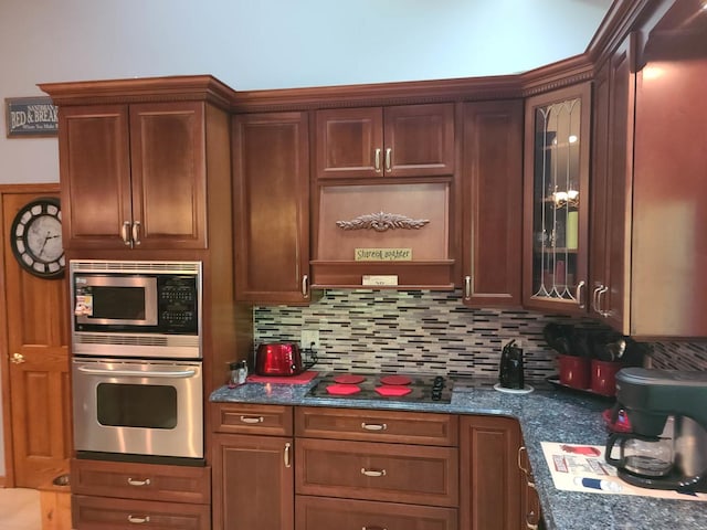 kitchen featuring tasteful backsplash, appliances with stainless steel finishes, custom exhaust hood, and dark stone countertops