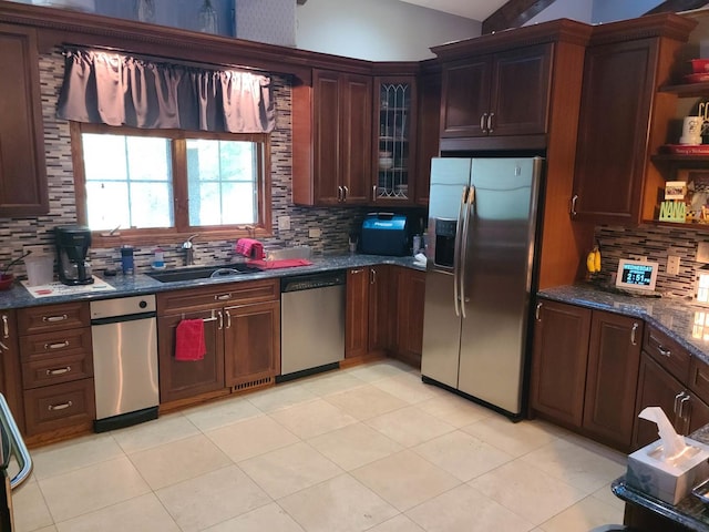 kitchen with stainless steel appliances, sink, dark stone countertops, and decorative backsplash