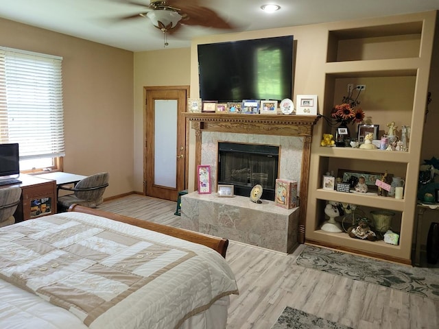 bedroom with ceiling fan, a high end fireplace, and light wood-type flooring