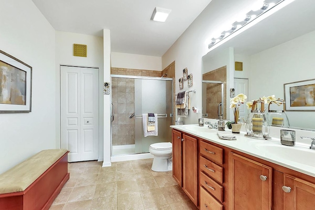 bathroom with tile patterned floors, vanity, toilet, and a shower with shower door