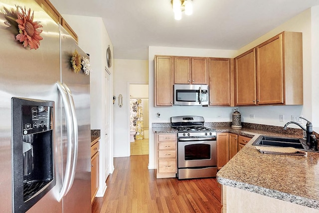 kitchen featuring stainless steel appliances, sink, and light hardwood / wood-style flooring