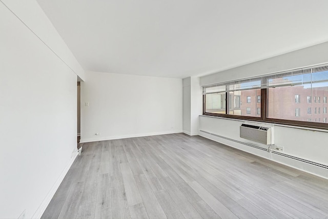 spare room with a wall mounted air conditioner and light hardwood / wood-style floors