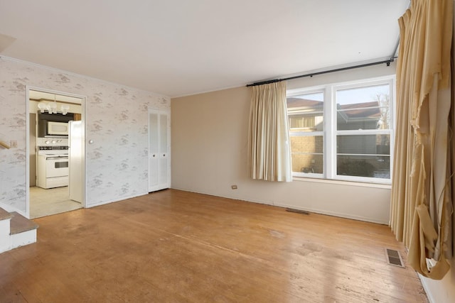 empty room with an inviting chandelier and light hardwood / wood-style floors