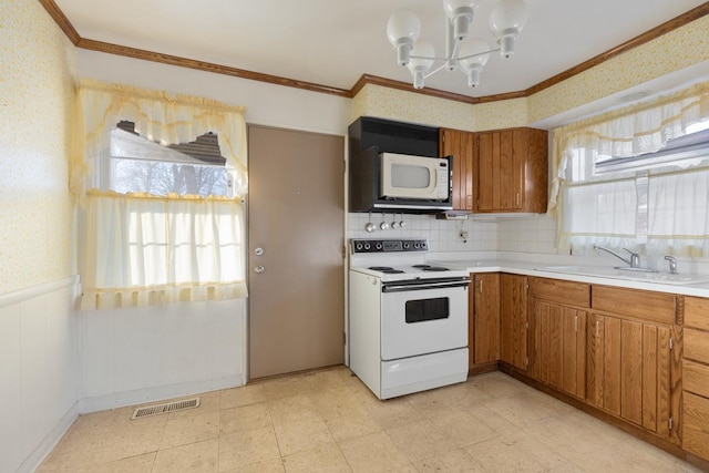 kitchen featuring crown molding, sink, white appliances, and a chandelier