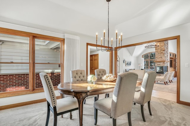 dining area featuring lofted ceiling, a chandelier, light colored carpet, and a fireplace