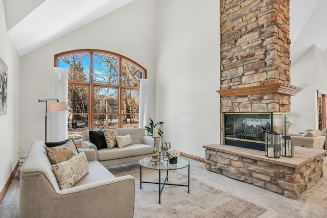 carpeted living room with a stone fireplace and high vaulted ceiling