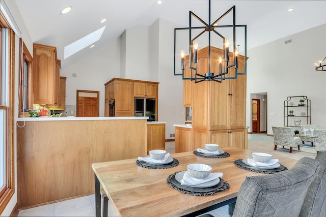 tiled dining space featuring a skylight, a chandelier, and high vaulted ceiling