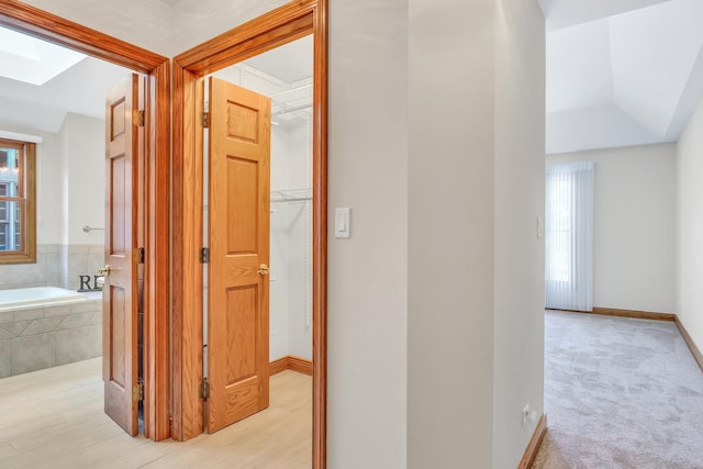 hallway with a skylight and light colored carpet