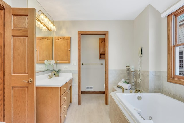 bathroom with vanity, wood-type flooring, and tiled bath