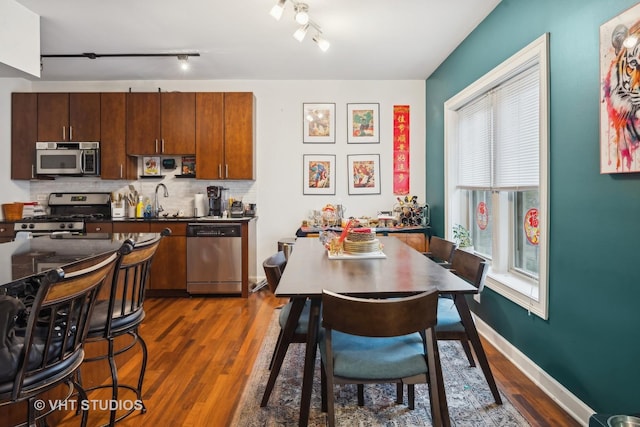 kitchen with sink, stainless steel appliances, dark hardwood / wood-style floors, track lighting, and decorative backsplash