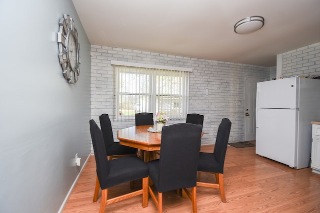 dining area featuring brick wall and light hardwood / wood-style floors