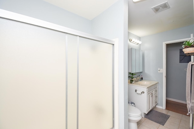 bathroom featuring vanity, a shower with shower door, tile patterned floors, and toilet