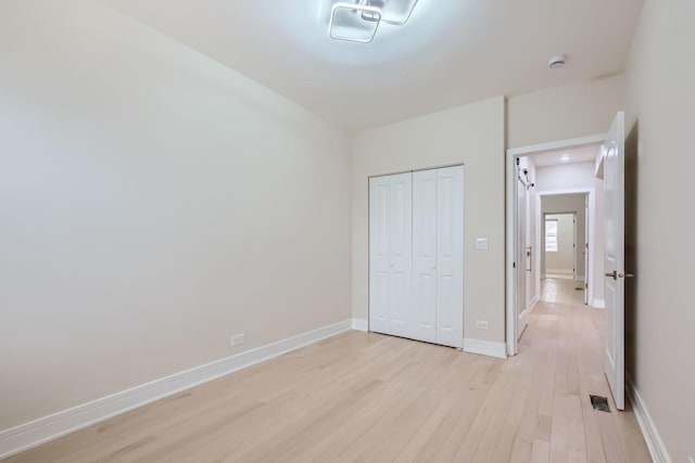 unfurnished bedroom featuring light wood-type flooring and a closet