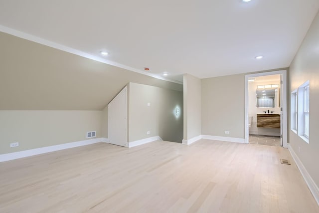 additional living space with vaulted ceiling and light hardwood / wood-style flooring