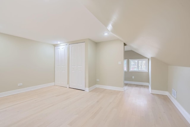 additional living space featuring vaulted ceiling and light wood-type flooring