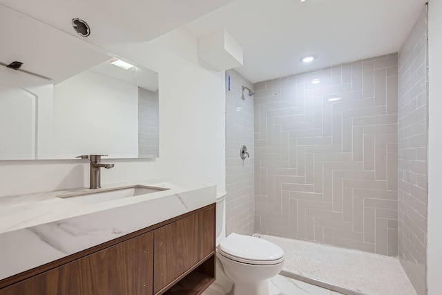 bathroom with vanity, toilet, and tiled shower