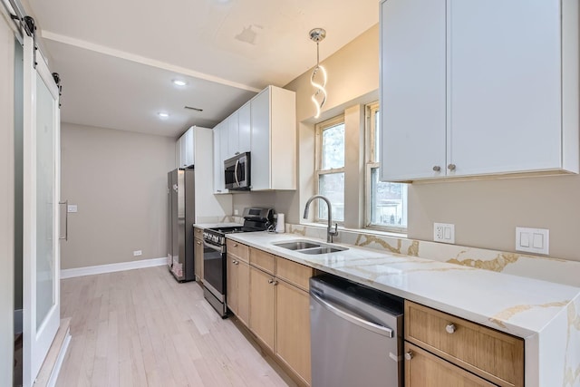 kitchen with sink, pendant lighting, stainless steel appliances, light stone countertops, and white cabinets