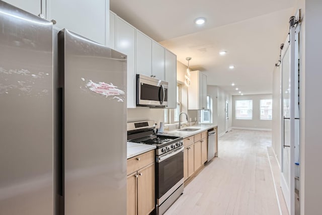 kitchen with sink, white cabinetry, stainless steel appliances, decorative light fixtures, and light brown cabinets