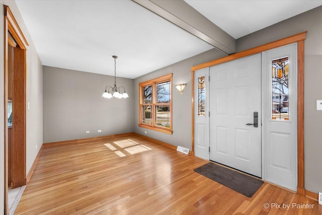 entryway featuring light wood-type flooring, visible vents, beam ceiling, an inviting chandelier, and baseboards