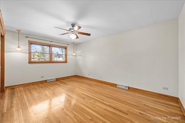 empty room with baseboards, visible vents, a ceiling fan, and light wood-style floors