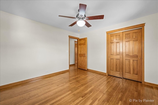 unfurnished bedroom with a closet, ceiling fan, baseboards, and wood finished floors