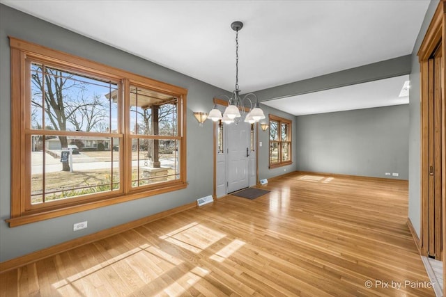 unfurnished dining area featuring a notable chandelier, visible vents, light wood-style flooring, and baseboards