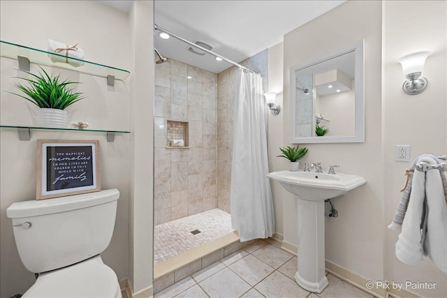 full bathroom with baseboards, a tile shower, a sink, tile patterned flooring, and toilet