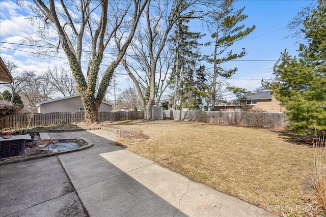 view of yard featuring an outdoor structure, a fenced backyard, a storage shed, and a patio area