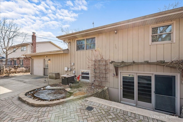 rear view of property featuring an attached garage and driveway