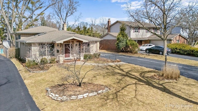 view of front facade with aphalt driveway, a shingled roof, and brick siding