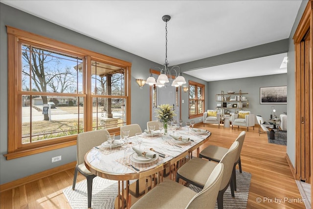 dining area featuring a chandelier, light wood finished floors, and baseboards