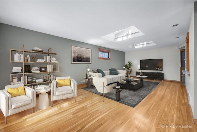 living room with a skylight, wood finished floors, and baseboards