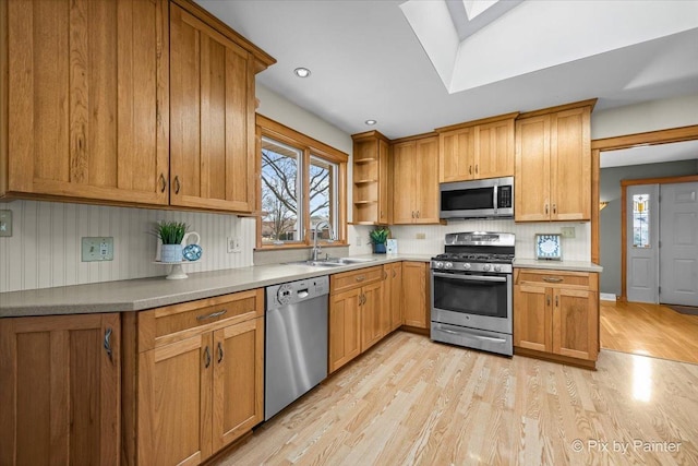 kitchen with light wood-style flooring, open shelves, tasteful backsplash, appliances with stainless steel finishes, and a skylight