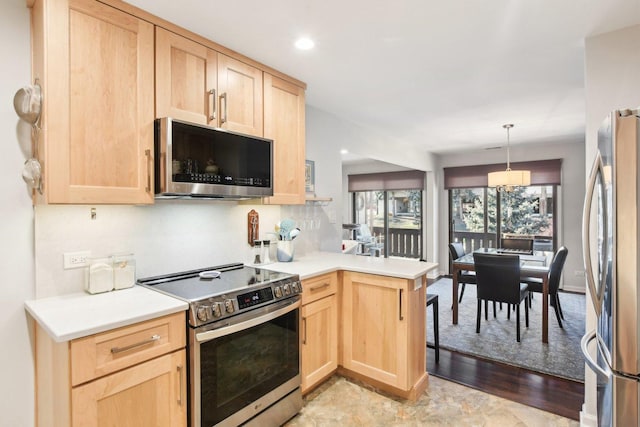 kitchen with light brown cabinets, kitchen peninsula, and appliances with stainless steel finishes