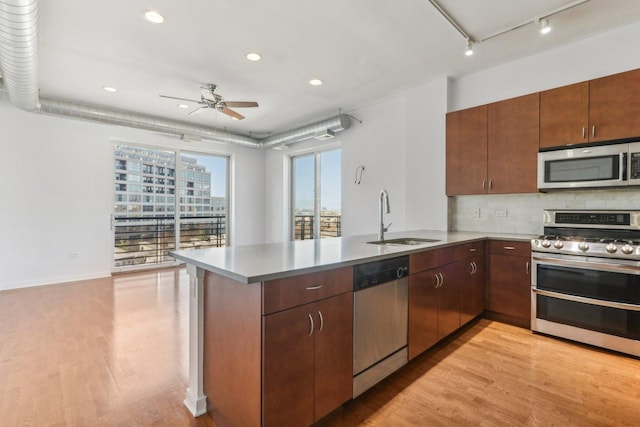 kitchen featuring stainless steel appliances, sink, light hardwood / wood-style flooring, and kitchen peninsula