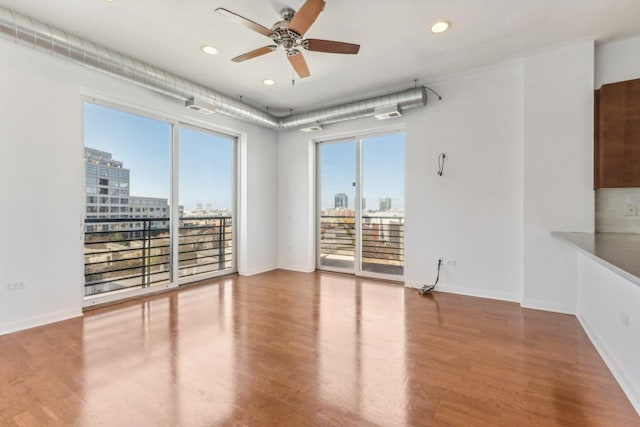 spare room featuring wood-type flooring, plenty of natural light, and ceiling fan