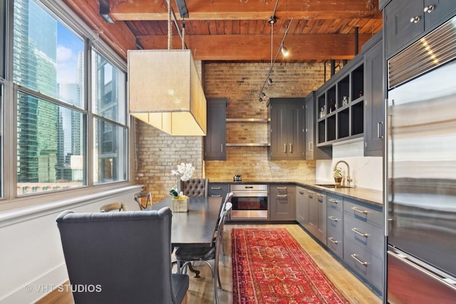 kitchen featuring a wealth of natural light, beamed ceiling, hanging light fixtures, stainless steel appliances, and wooden ceiling