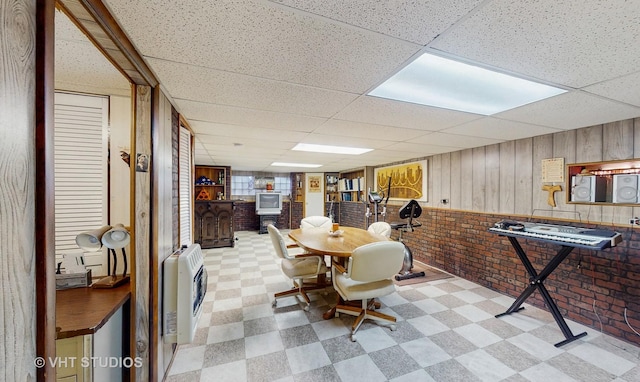 dining area featuring brick wall, heating unit, and a drop ceiling