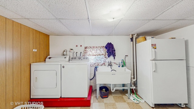 laundry room featuring washing machine and clothes dryer and wood walls