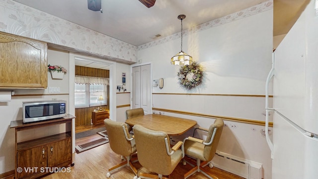 dining area with a baseboard radiator, ceiling fan, and light hardwood / wood-style flooring